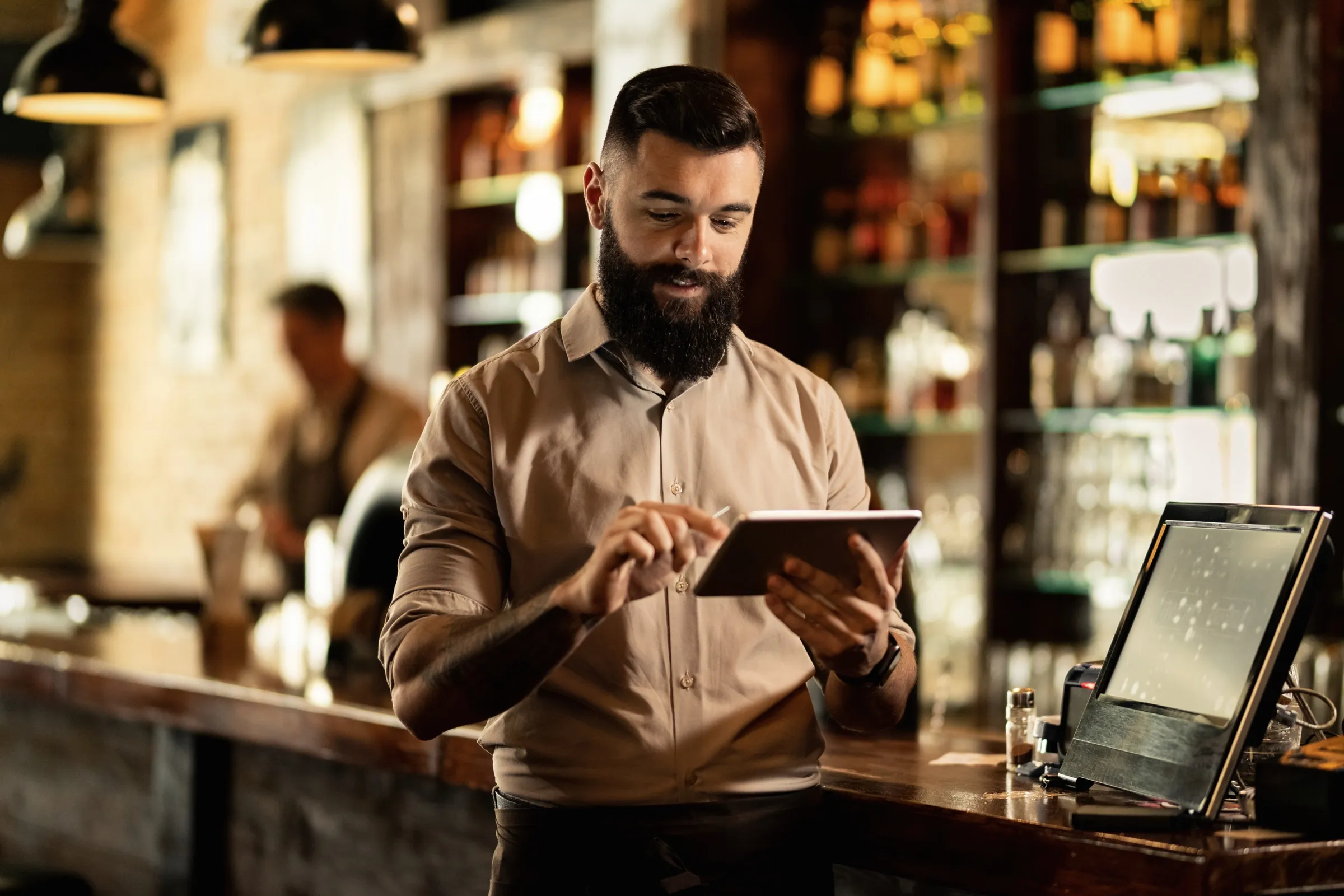 Barista usando una tablet en la barra de un restaurante, junto al punto de venta
